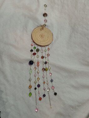 Handmade hanging decoration featuring handcrafted glass beads on a wooden base